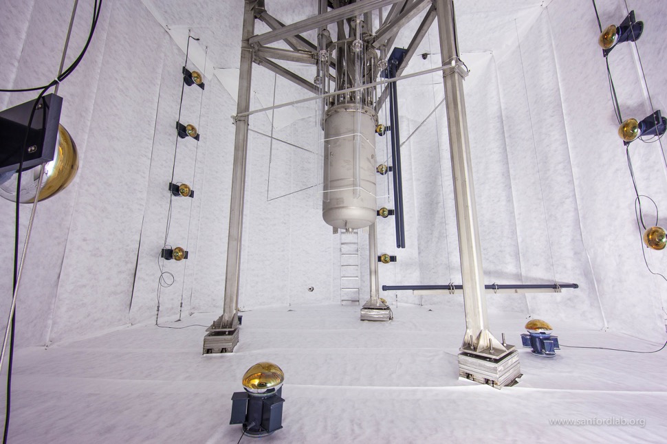 Interior of the empty LUX water tank with the titanium cryostat suspended at center and the neutron conduit hanging horizontally at right